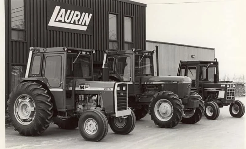 Three tractors fitted with Laurin cabs parked in front of the Laurin building, around 1985